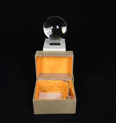 une boîte ouverte contenant une boule de cristal, sur fond noir