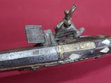 un vieux pistolet surmonté d'un homme, sur fond rouge