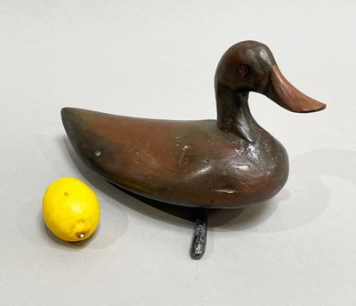 un canard en bois posé à côté d'un citron sur une table