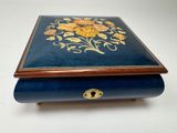 une boîte bleue ornée de fleurs dorées sur un fond blanc