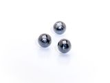 three black glass beads on a white surface with a white background
