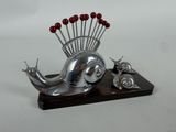 une sculpture en argent représentant un escargot, posée sur un socle en bois