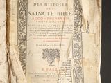 Un vieux livre est ouvert sur une table, sur fond noir.