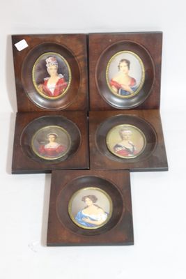 four miniature portraits of women in wooden frames on a white surface