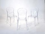 three clear chairs sitting in front of a white backdrop