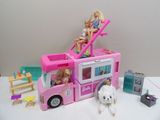 deux poupées Barbie assises sur le toit d'un petit bus rose