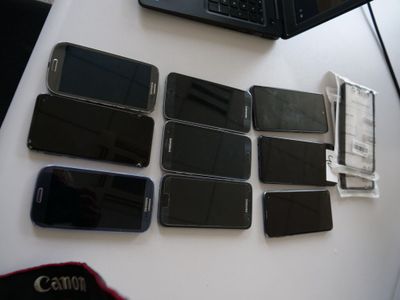 Plusieurs téléphones portables sont posés sur une table à côté d'un ordinateur portable