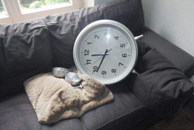 une horloge posée sur un canapé recouvert d'une couverture