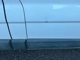 le côté d'une voiture blanche à laquelle il manque la poignée de porte