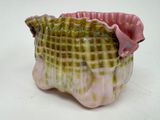 a pink and green vase sitting on a white surface