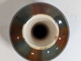 a brown and blue vase sitting on a white table