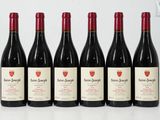 six bottles of wine are lined up on a white surface