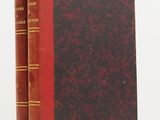 two red books sitting on top of each other on a white surface