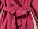 the coat is pink and has a black button on the front