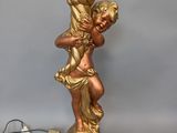 a gold statue of a child holding a lamp