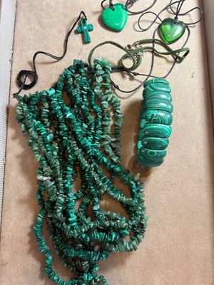 Des colliers et des bracelets verts sont présentés dans une boîte posée sur une table