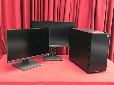 deux écrans d'ordinateur posés sur une table rouge, avec des rideaux rouges