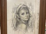 drawing of a girl in a frame on a table in front of a window