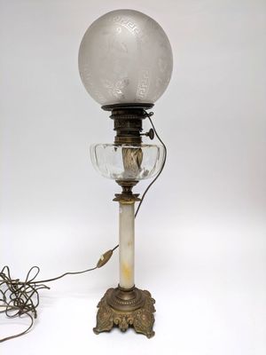 an old fashioned lamp with a glass shade on top of it