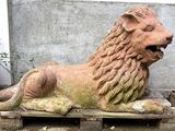 a statue of a lion sitting on a pallet next to a potted plant