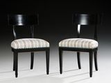 pair of black chairs with striped upholstered seats against a black background