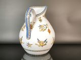 a white pitcher with blue and gold designs on it