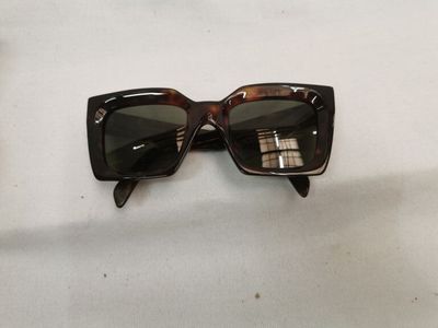 des lunettes de soleil posées sur une table recouverte d'une nappe blanche, à côté d'une paire de lunettes