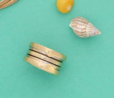 une bague en or ornée d'un coquillage, à côté d'autres bagues
