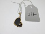 une photo d'un pendentif noir en forme de cœur sur lequel est accrochée une étiquette de prix