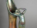 a silver vase with a woman holding a spoon in it