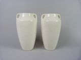 two white vases that are sitting on a table