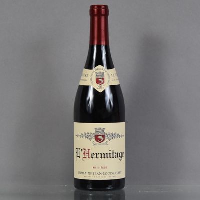 the bottle of red wine is sitting on a glass table