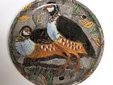 two birds sitting on a plate with leaves on it