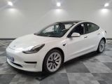 the white tesla model 3 is parked in a clean room