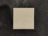 a square piece of paper on a black surface