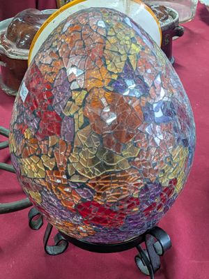 un œuf en verre coloré posé sur un socle, sur une table