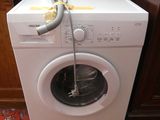 une machine à laver blanche à laquelle est raccordé un tuyau
