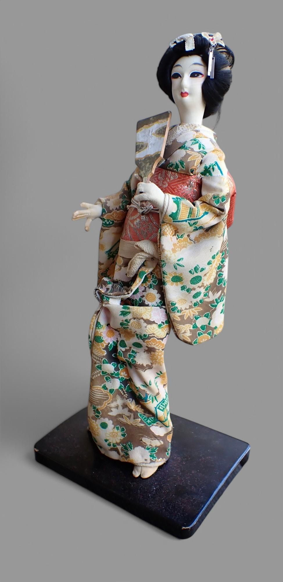 Japon : poupée geisha habillée d'un kimono à décor floral, tenant un éventail, H : 36 cm environ. Petites usures.