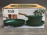 two green pots and pans sitting on a table