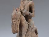 an old wooden statue of a man riding a horse with a helmet on