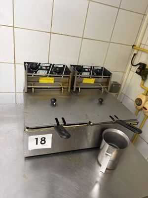 a metal counter with three burners and a bucket on it