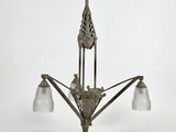 un lustre ancien muni de trois abat-jours en verre suspendu au plafond