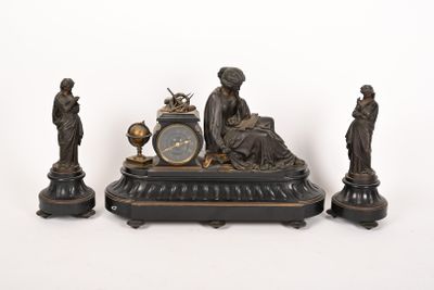 three statues and a clock sitting on a table