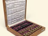 an open wooden box with chess pieces in it on a white surface