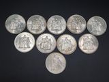 six different types of silver coins on a black surface