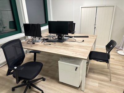 un bureau sur lequel sont posés deux écrans d'ordinateur et une chaise noire