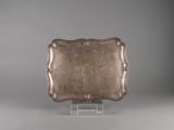an antique silver plate on a clear stand on a gray background