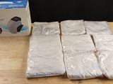 de nombreux sacs en plastique blanc posés sur une table à côté d'une boîte de papier toilette