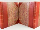 an open book with a red cover sitting on top of a white table