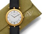 an image of a gold and black watch on a green case